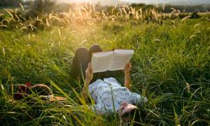 Student lying in grass reading