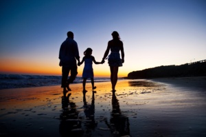 Family walking on beach at sunset